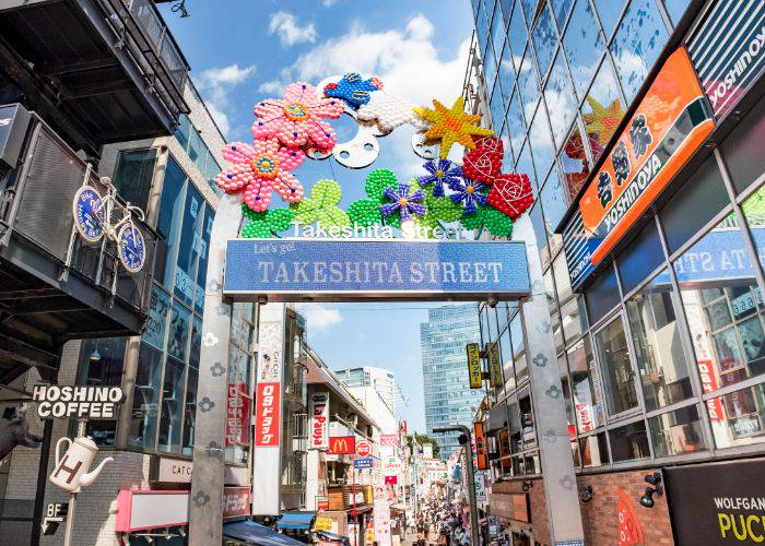 The entrance to Takeshita Street in Harajuku on a sunny day.